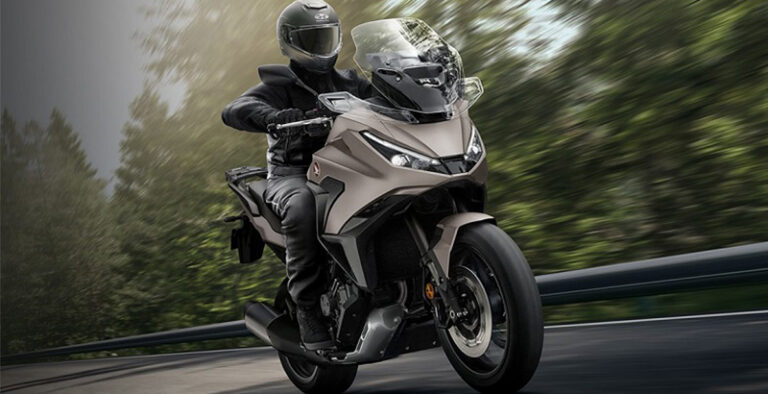 Motorcycle with a rider in full gear leaning into a curve on a winding road on a bronze-colored bike.